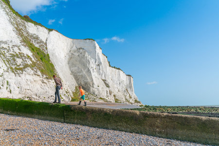 Dover England - August 19 2019; Man and boy walk from beach towards face of White Cliffs of Dover.の写真素材