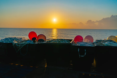 Boats and nautical gear silhouetted by rising sun on Deal beach, Kent United Kingdom.