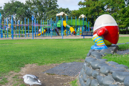 Tauranga Memorial Park Children's Playground with Humpty-Dumpty sitting on low wall looking over...