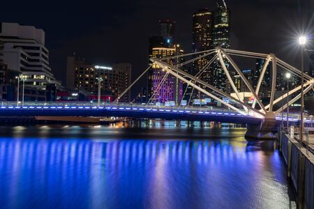 Melbourne Australia - March 14 2020; View down Yarra River towards Seafarers Bridge and lights of city buildings in long exposure with coloured glows reflecting of water.の写真素材