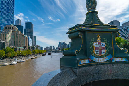 Melbourne, Australia - March 9 2020; Princes Bridge with focus on city coat of arms and motto which translates to  'We gather strength as we go' and Southbank skyline across Yarra River.のeditorial素材