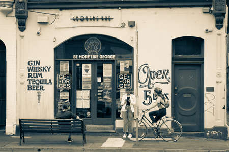 Melbourne Australia - March 13 2020; Split toned old-fashioned style image people, yougn woman on mobile, man sitting outside and passing cyclist  outside Georges Bar in Fitzroyのeditorial素材