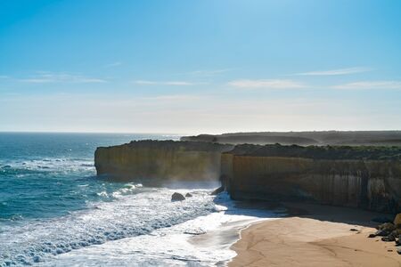Sheer limestone cliff faces along Great Ocean Road coastal road trip with sea spay from crashing waves below in Victoria Australia.の写真素材