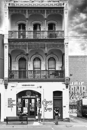 Melbourne Australia - March 13 2020; Split toned old-fashioned style image two people on mobiles, man sitting outside  outside Georges Bar in Fitzroyのeditorial素材