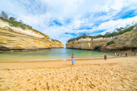 Victoria Australia - March 17 2020; tourists on protected bay in Loch Ard Gorge surrounded by high limestone walls and water washing in across beach.のeditorial素材