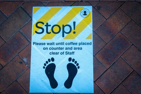 STOP Social Distancing Signage or Floor Sticker for help reduce the risk of catching coronavirus Covid-19 on footpath outrside cafe.の写真素材