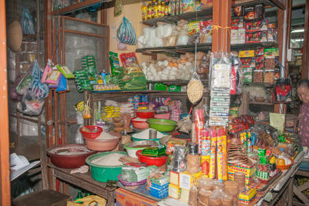 Hoi An Vietnam October 19 2013; Asian market food stall with bench and shelves packed with selection of food ingredients and other household items.のeditorial素材