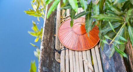 Myanmar Travel Images boat with bamboo floor and coical hat in selective focus beyong green blurred leaves in blue water,の写真素材