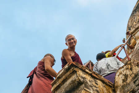 Bagan Myanmar - October 29 2013; Monk climbing steps up a stupa looks over edge and smiles calmly.のeditorial素材