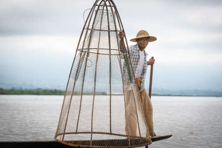 Inle Lake Myanmar - November 2 2013; Portrait of fisherman holding unique style  conical net ready to use from from narrow boat.のeditorial素材