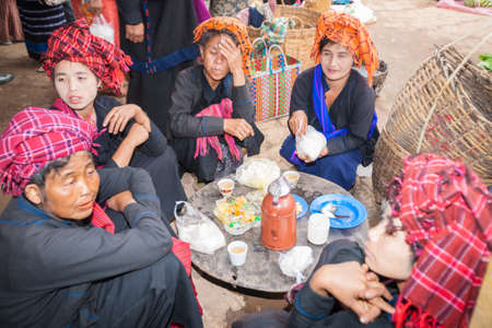 Inle lake Myanmar - November 3 2013; Asian Market with women in traditional headscarves sitting on ground around meal .のeditorial素材