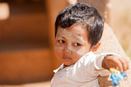 Inle Lake Myanmar - November 3 2013; Boy with face daubed  with thanaka looking sideways thinking.のeditorial素材