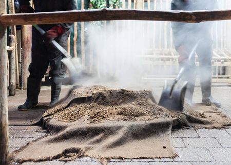 Smoke and dust fly as food is being prepared for a traditional maori feast or Hangi, by steaming through heat from underground thermal activity or heated stones in base of pit.の写真素材