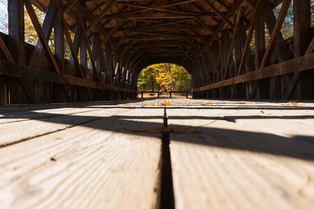 View along platform of Sunday River covered bridge with structure casting shadow pattern and leading lines. Sunday River, Maine, USA.の写真素材