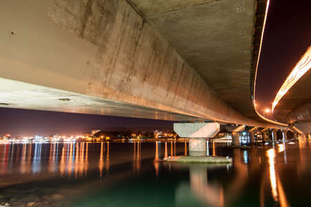 Under Tauranga Harbour Bridge at night with city lights across harbour.の写真素材