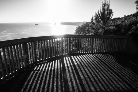 Lookout barrier with long shadows of structure on Coromandel coast in monochrome.