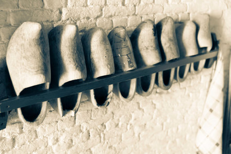 Row of Dutch clogs in rack on wall in selective focus and monochrome old-world effect.
