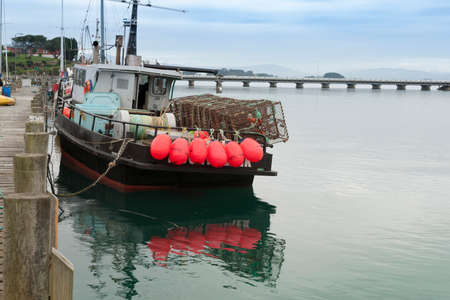 Riverton New Zealand - February 27 2015; Fishing boat with bright pink buoys tied to stern rail at pier in Riverton South Island New Zealand.のeditorial素材