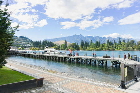 Queenstown New Zealand - March 1 2015; Pier projecting into scenic Lake Wakatipu at with tourists.のeditorial素材