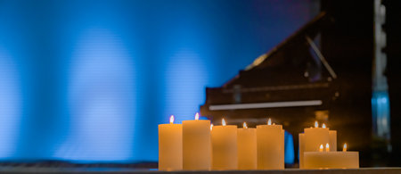 Candles on a stage with grand piano in background.の写真素材