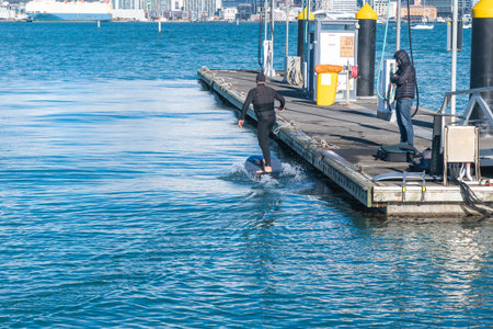 Auckland New Zealand - June 17 2021;Foil boarder landing at pier after tow around bay behind jet-ski...