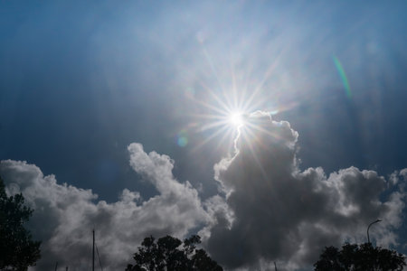 Sun bursts above cloud against blue sky.の写真素材