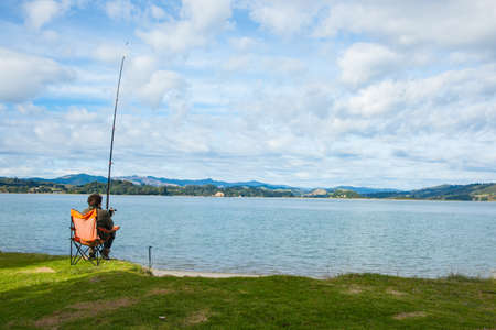 Whakatane New Zealand - May 26 2012; Lone fisher at Ohiwa Harbour rear view patiently and hopefully waiting.のeditorial素材