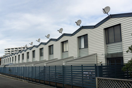 Long row of repeating gables and television dishes on small urban apartments from street modern...