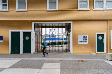 Wellington New Zealand - July 29 2021; Woman blurred in motion jogs past brown weatherboard building...