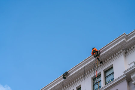 Wellington New Zealand - July 29 2021; Roped up and on the edge of high roof of building a building cleaner is working and managing the dangerのeditorial素材