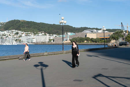 Wellington New Zealand - July 29 2021; Late afternoon long shadows and people passing on old wharf promenade on city waterfrontのeditorial素材