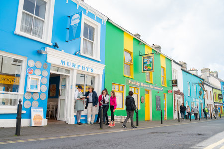 Dingle Ireland - August 12 2017; People on street outside brightly colored shop and bar facades in the historic fishing and popular tourism town.のeditorial素材