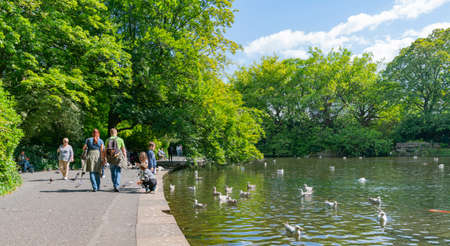 DUBLIN, IRELAND - AUGUST 10; People walk leisurely around lake in public park of St. Stephens Green in cityのeditorial素材