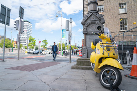 Dublin Ireland - August 9 2017; Yellow motor-scooter parked and locked on footpath of city street.