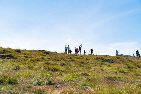Ireland - August 13 2017; Group of tourists on ridge beyond slope against blue sky taking in views and photographing the Wild Atlantic Wayのeditorial素材