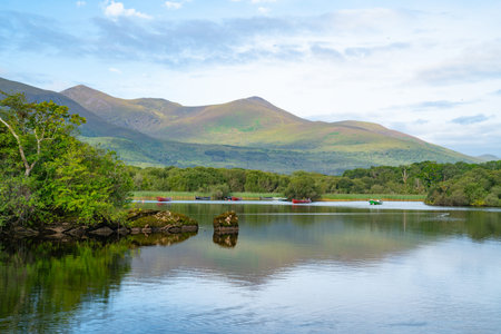 Scenic view across Lake Ross to boats on other-side and distant mountains with light and shadow from...