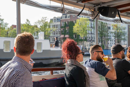 Amsterdam Netherlands - August 17 2017; People on city canal cruise with male drinking glass of beerのeditorial素材