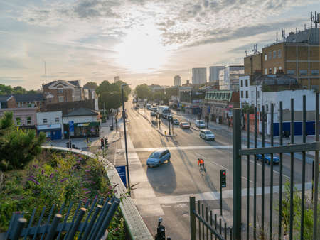 London, England - August 7 2017; Sunsets at far end Mile End Road with vehicles moving along the street, people and buildings from overpass, Bow Londonのeditorial素材