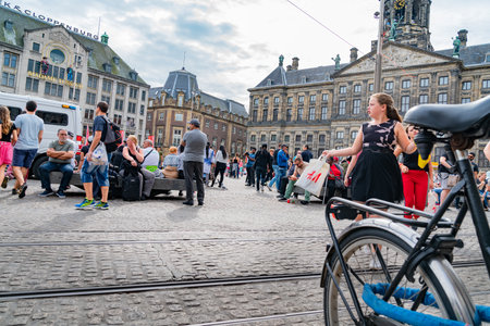 Amsterdam Holland - August 17 2021; People fill popular meeting place and tourist attraction Dam Square in city surrounded by historic buildings.のeditorial素材