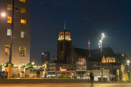 Rotterdam Netherlands - August 23 2017;Magnificent clock tower building  of St. Lawrence Church in background of city square illuminated at night with blurred figure of person in foregroundのeditorial素材