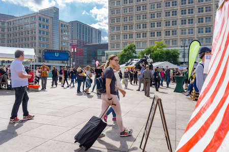 Berlin, Germany - August 28 2017; People in street, Alexanderplatz, wide cobbled pedestrian area in city with tourist pulling travel bag.のeditorial素材