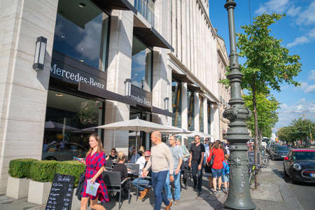 Berlin Germany - August 26 2017; People move along city pavement past cafes and Mercedes Benz showroomのeditorial素材