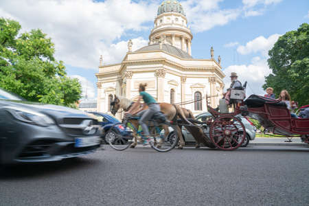 Berlin, Germany - September 25, 2017: Traditional style building with brass dome and gold statue with three modes of transport blurred in motion passing on street.のeditorial素材
