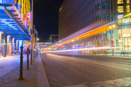 Berlin Germany - August 25 2017; Friedrichstrasse at night illuminated by street lights and neon signs with rail tracks leading into distance along light trails form passing vehicles.のeditorial素材