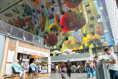 Rotterdam Netherlands - August 2017; People mingle and buy food in Rotterdam Market Hall in city, modern structure with rounded roof profile and interior painted ceiling mural.のeditorial素材