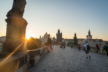 Prague, Czech Republic - August 29 2017; Early morning light as people pass historic statues at...