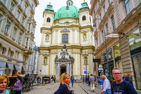 Vienna Austria - September 3 2017; Iconic green dome and entrance of St Peter's church at end of narrow street lined by traditional buildings.のeditorial素材