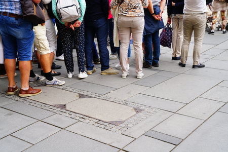 Group of people standing facing away from waist down in city street