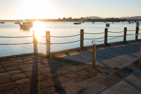 Dawn with silhouettes back-lit by rising sun on Tauranga waterfront, New Zealand.の写真素材