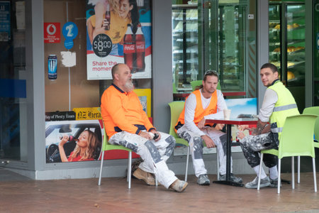 Tauranga new Zealand - December 7 2021; Construction workers in high visibility fluorescent vests sitting outside a bakery breakfasting before starting days workのeditorial素材